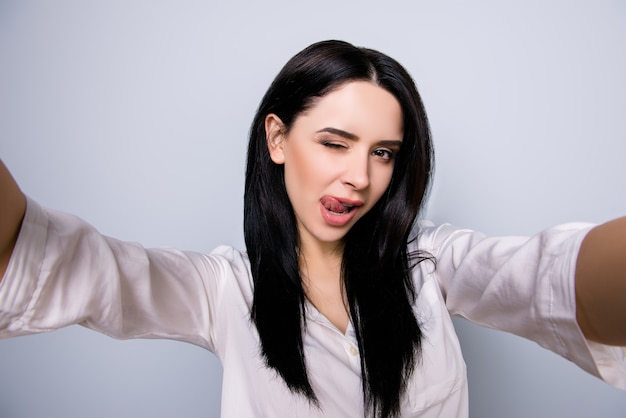 Portrait of sexy beautiful young  woman licks her lips and making selfie photo