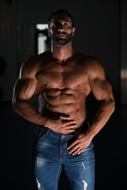 Portrait of a sexy muscular man in pants posing after exercise in gym