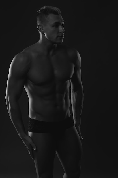 Photo portrait of a sexy muscular young man posing over dark background