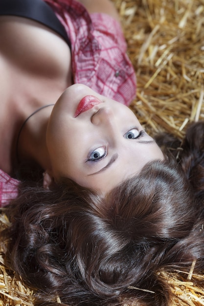 Portrait of the sexy woman is lying on hay