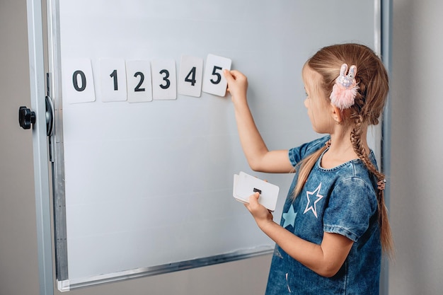 Portrait of sharming cute intelligent kid arranging numbers in the correct order. Lovely child holding a card with number 5. Concept of study. photo with noise