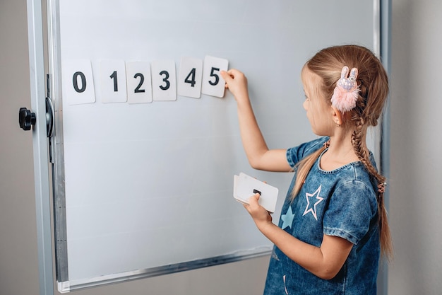 Portrait of sharming pretty beautiful kid arranging numbers in the correct order. Adorable child holding a card with number 5. Concept of mathematics. photo with noise