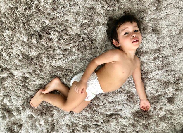 Photo portrait of shirtless boy lying on carpet