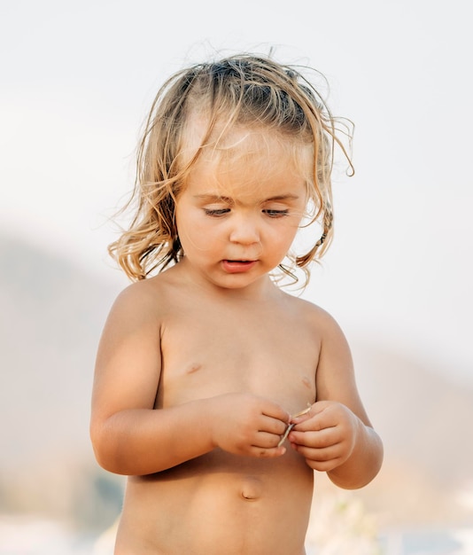 Photo portrait of shirtless boy standing against wall