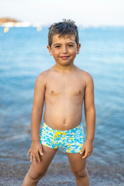 Photo portrait of shirtless boy standing in sea