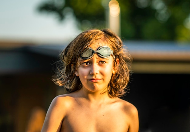 Photo portrait of a shirtless boy wearing swimming glassed on his head