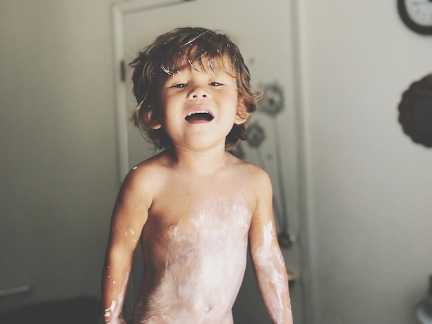 Portrait of shirtless boy with messy body standing at home