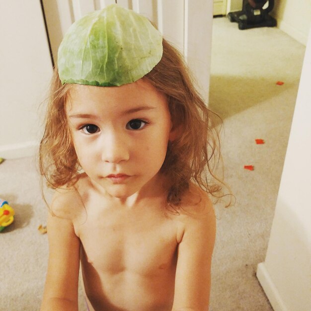 Photo portrait of shirtless girl with cabbage leaf on head at home