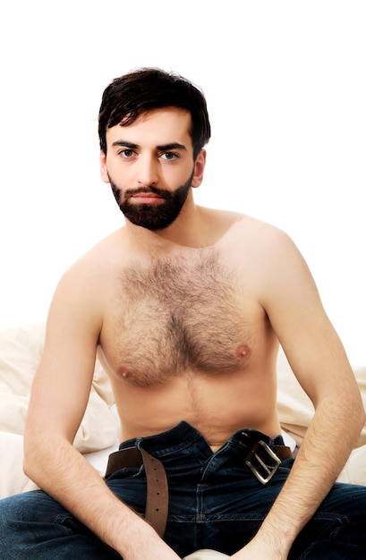 Photo portrait of shirtless man sitting on bed at home