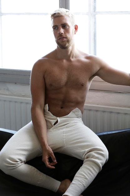 Photo portrait of shirtless man sitting on sofa at home