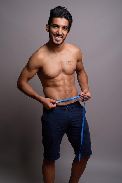 Photo portrait of shirtless man standing against gray background