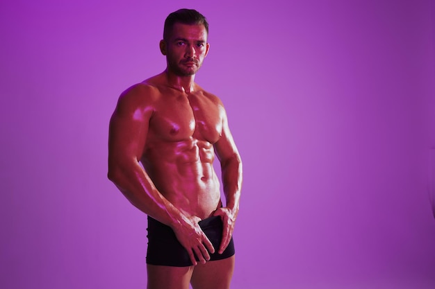 Portrait of shirtless man standing against gray background