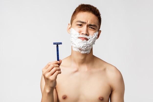 Foto ritratto di un uomo senza camicia in piedi su uno sfondo bianco