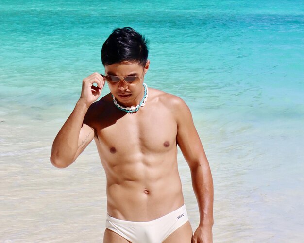 Portrait of shirtless man standing at beach