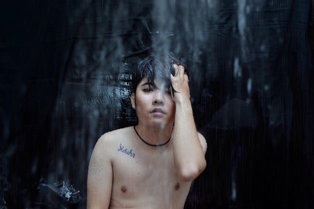 Portrait of shirtless man at waterfall