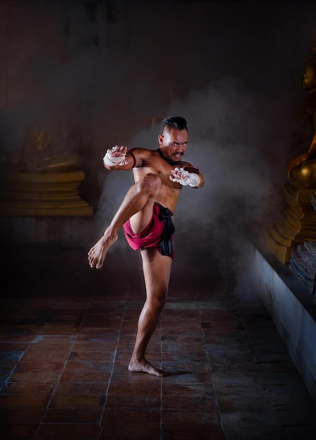 Photo portrait of shirtless mid adult man practicing muay thai at night