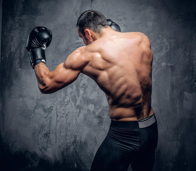 Portrait of shirtless muscular fighter from the back.