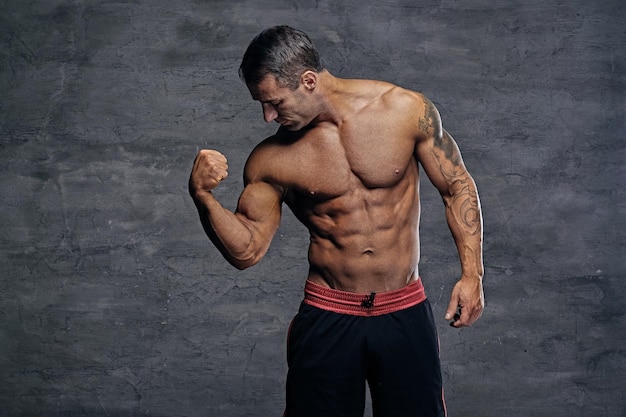 Portrait of shirtless muscular middle age male isolated with illumination on grey background.