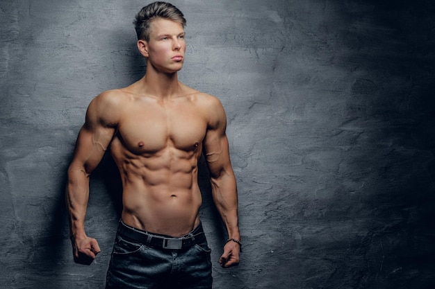 Portrait of shirtless strong muscular guy on grey background.