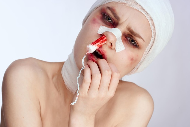 Photo portrait of shirtless woman applying lipstick against white background