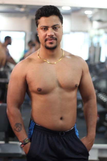 Photo portrait of shirtless young man standing at gym