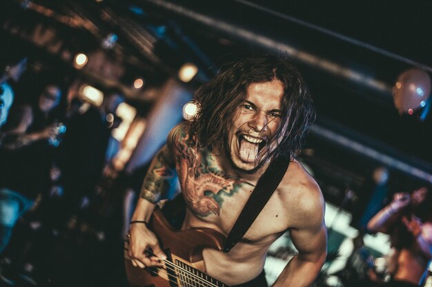portrait of shirtless young rock musician at nightclub