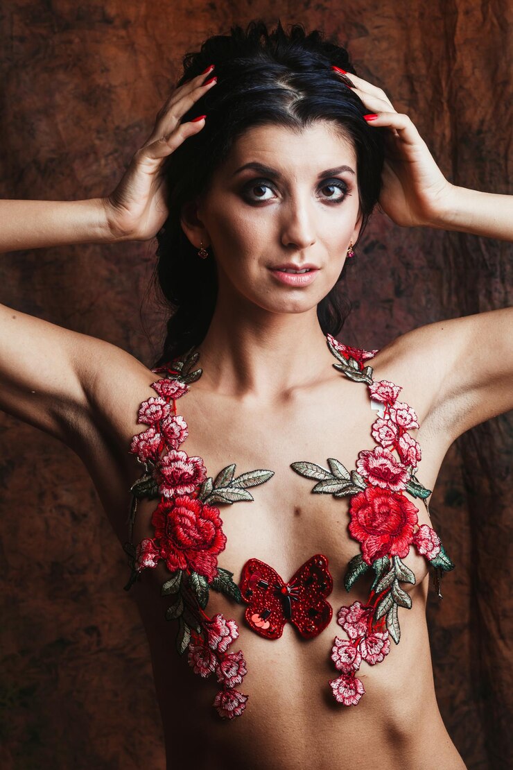 Photo portrait of shirtless young woman with floral decoration standing against wall