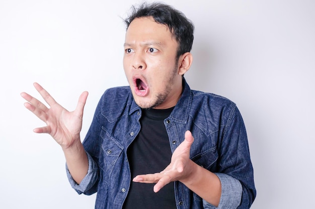 A portrait of a shocked Asian man wearing a navy blue shirt isolated by a white background