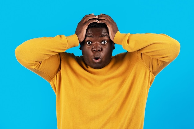 Portrait Of Shocked Black Young Man Opening Mouth And Touching Head