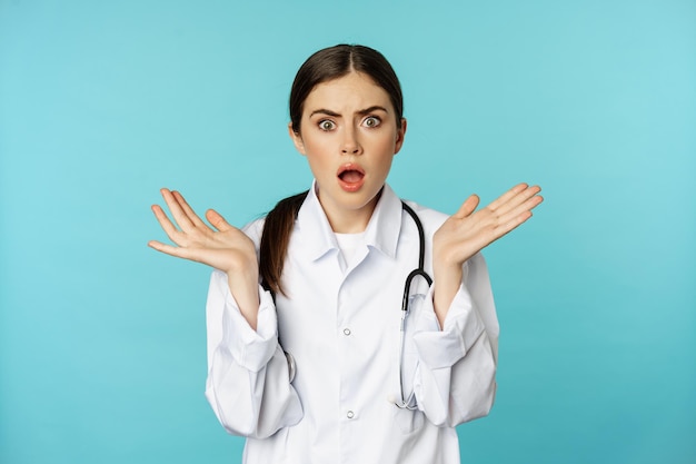 Portrait of shocked female doctor worried healtcare worker in white robe looking concerned at patien...