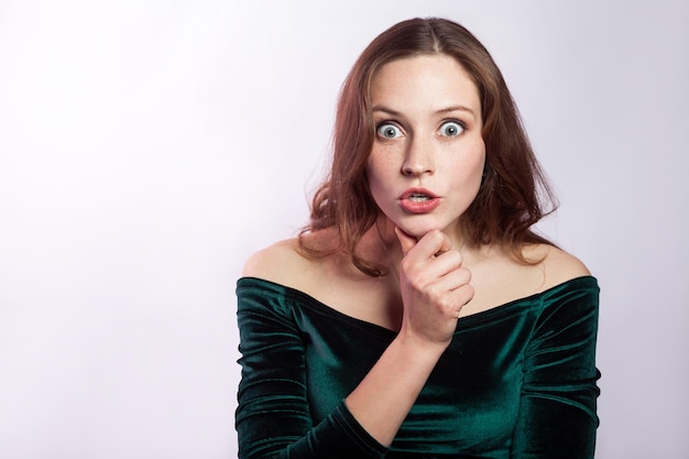 Portrait of shocked unbelieved woman with freckles and classic green dress