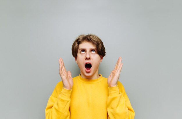 Portrait of shocked young man in bright clothes isolated on gray background