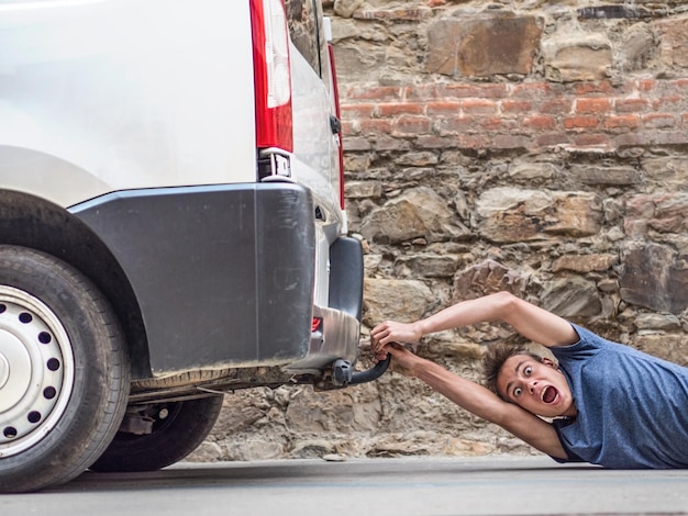 Photo portrait of shocked young man pulled by car on street