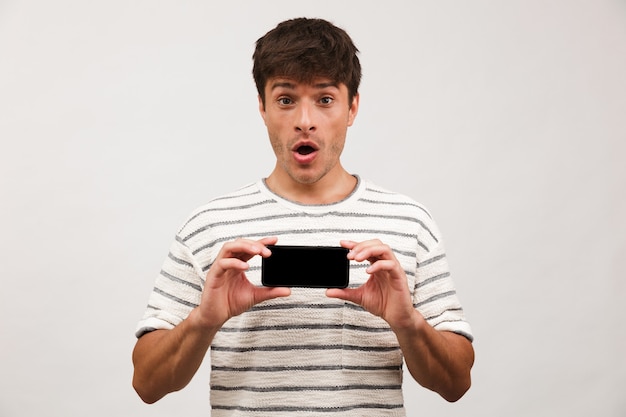 Portrait of a shocked young man standing isolated