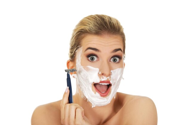 Portrait of shocked young woman shaving against white background