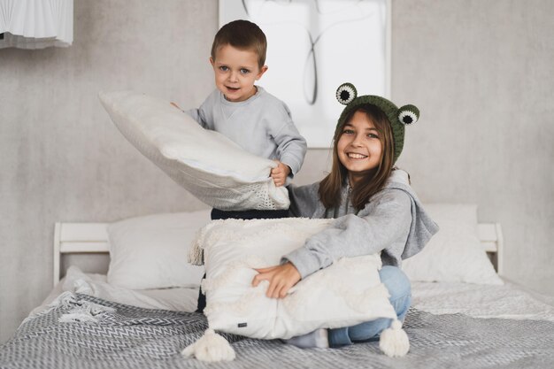 Photo portrait of sibling playing with pillow at home