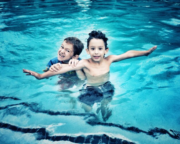 Portrait of siblings enjoying in swimming pool