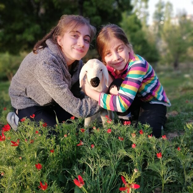 Photo portrait of siblings with kid goat on land