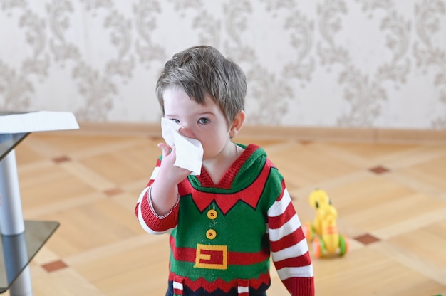 Portrait of a sick boy cleaning his nose with a napkin