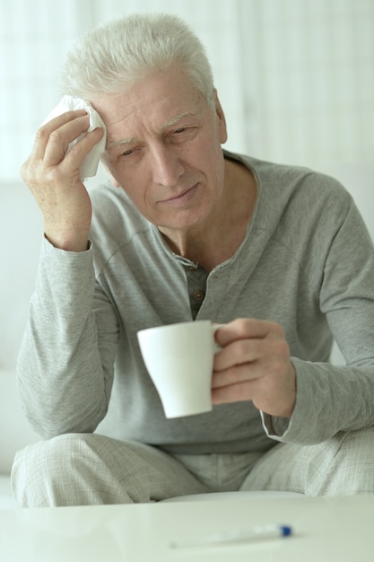 Portrait of sick elderly man with cup