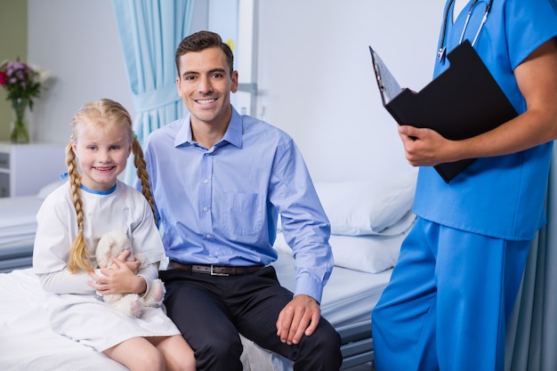 Portrait of sick girl and father in hospital bed