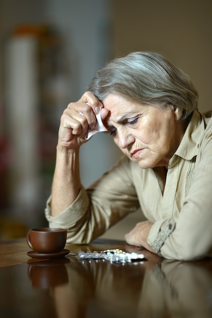 Portrait of a sick senior woman taking pills