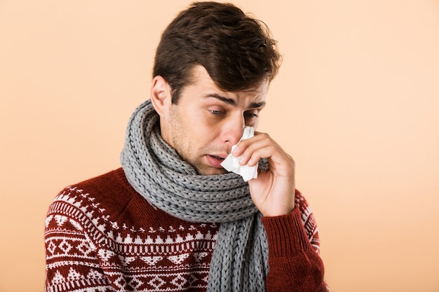 Portrait of a sick young man dressed in sweater and scarf