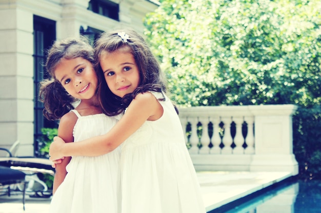 Portrait of sisters standing at poolside