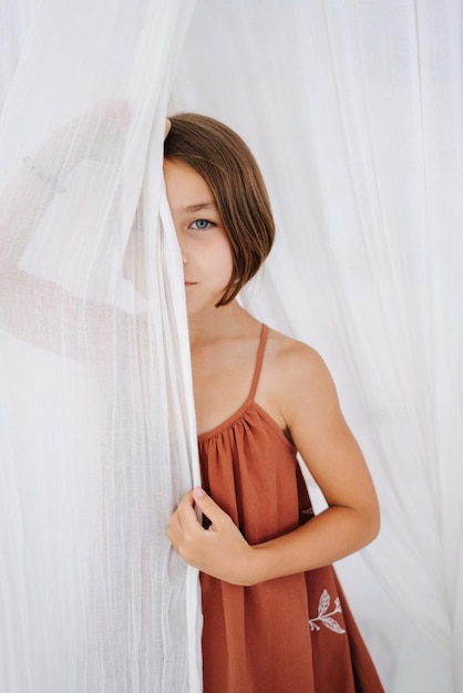 Foto ritratto di una bambina di sei anni tra le tende bianche