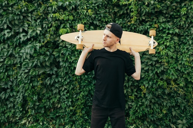 Portrait of skateboarder on green background with ivy plant