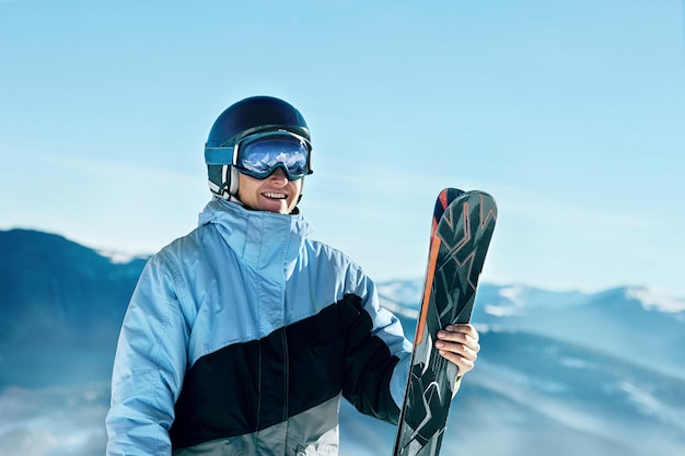 Portrait of a skier in the ski resort on the background of mountains and blue sky