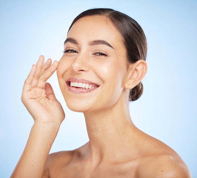 Portrait skincare and beauty with a model woman in studio on a blue background for natural treatment Face wellness and luxury with an attractive young female posing to promote a skin care product