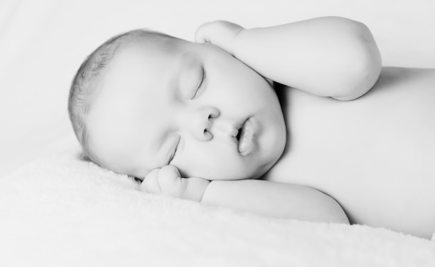 Portrait of sleeping newborn baby holding his hand close to face cute little child