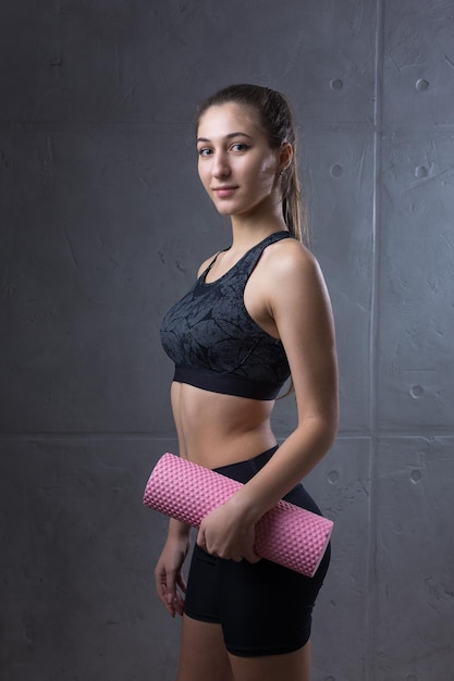 Portrait of a slender athletic young girl against a concrete wall in a fashionable apartment interior